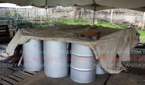 A tarpaulin drapes over the bass pans at the Desperadoes Steel Orchestra on Tragarete Road, Port of Spain